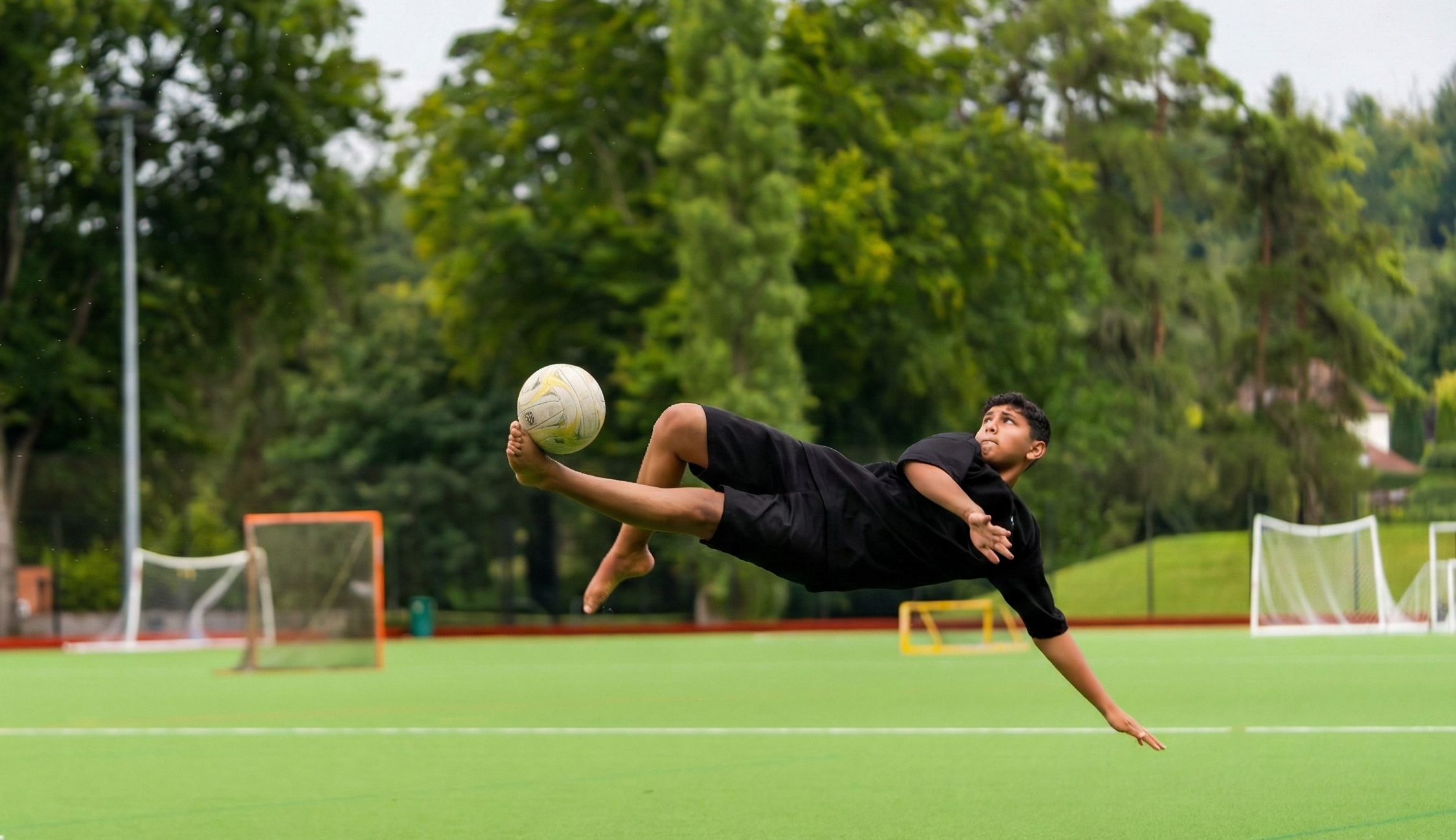 طالب يسدد كرة بمقصية في ملعب كرة القدم
